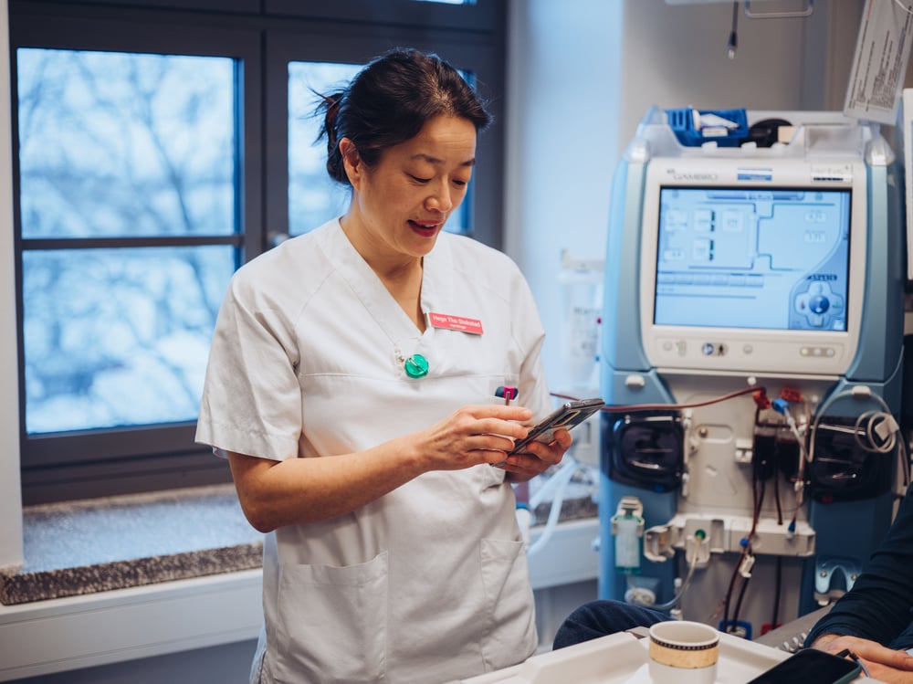 Lege som dokumenterer i journalen på mobilen