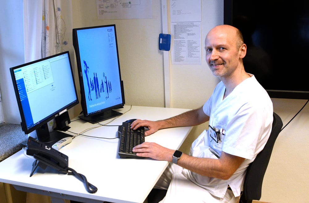 Bilde av en mann som sitter foran en PC og jobber med journalsystemet DIPS Arena - Henrik Sundt Moen