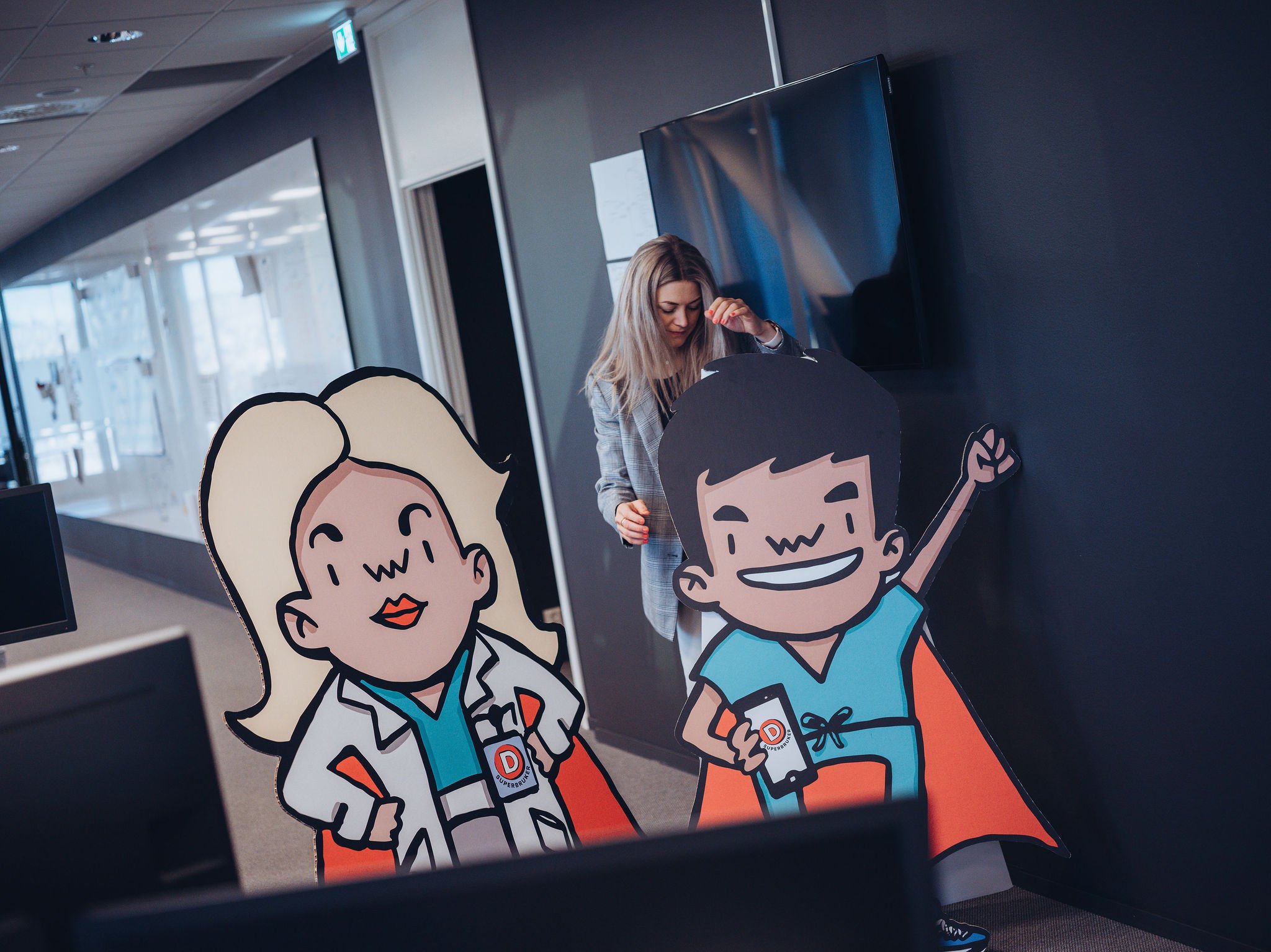Dame sammen med superhelt-figurer i kontorlandskap 2