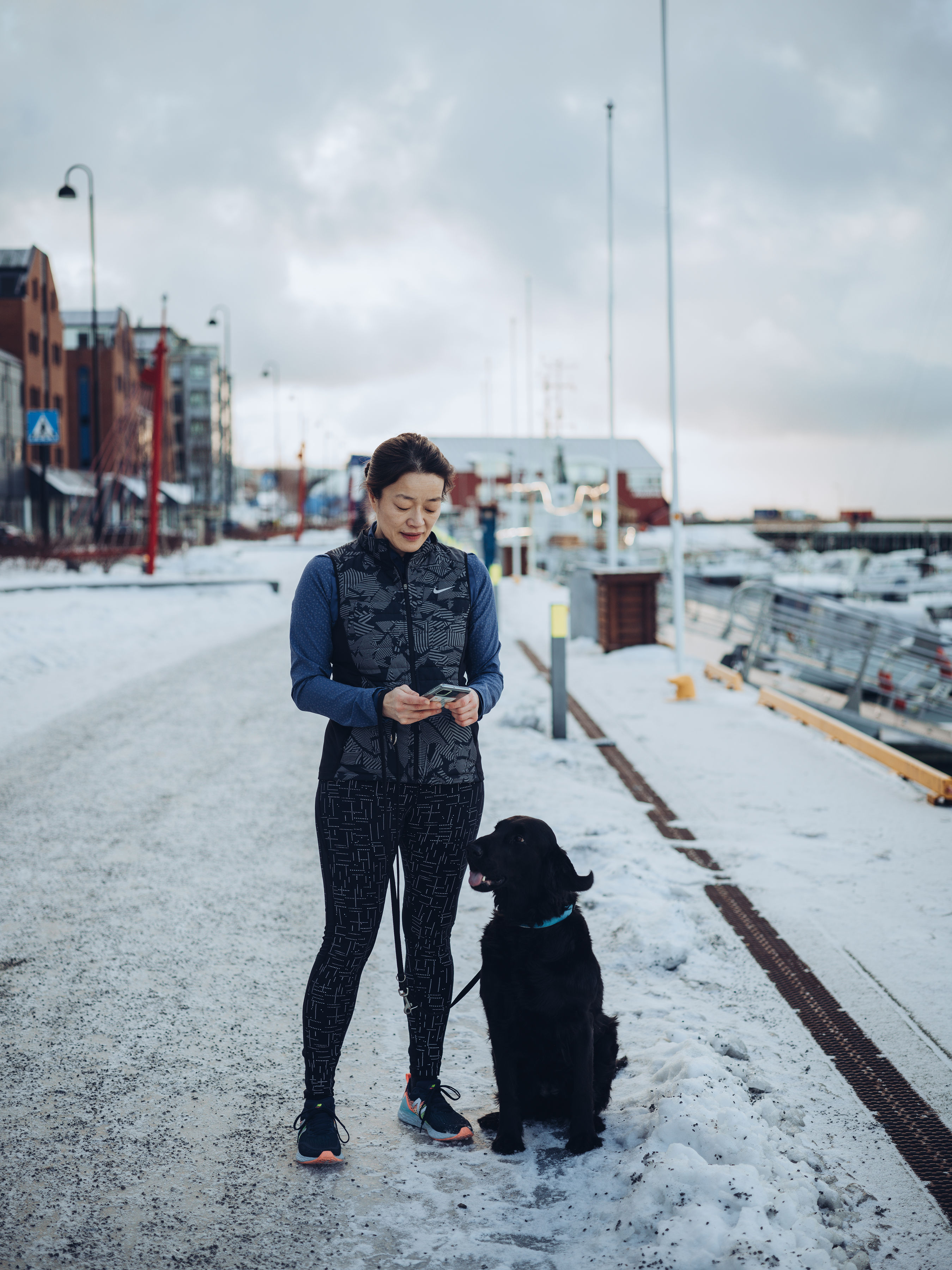 Lege som titter ned på Arena Mobil mens hun er på hjemmevakt og går tur med hunden.