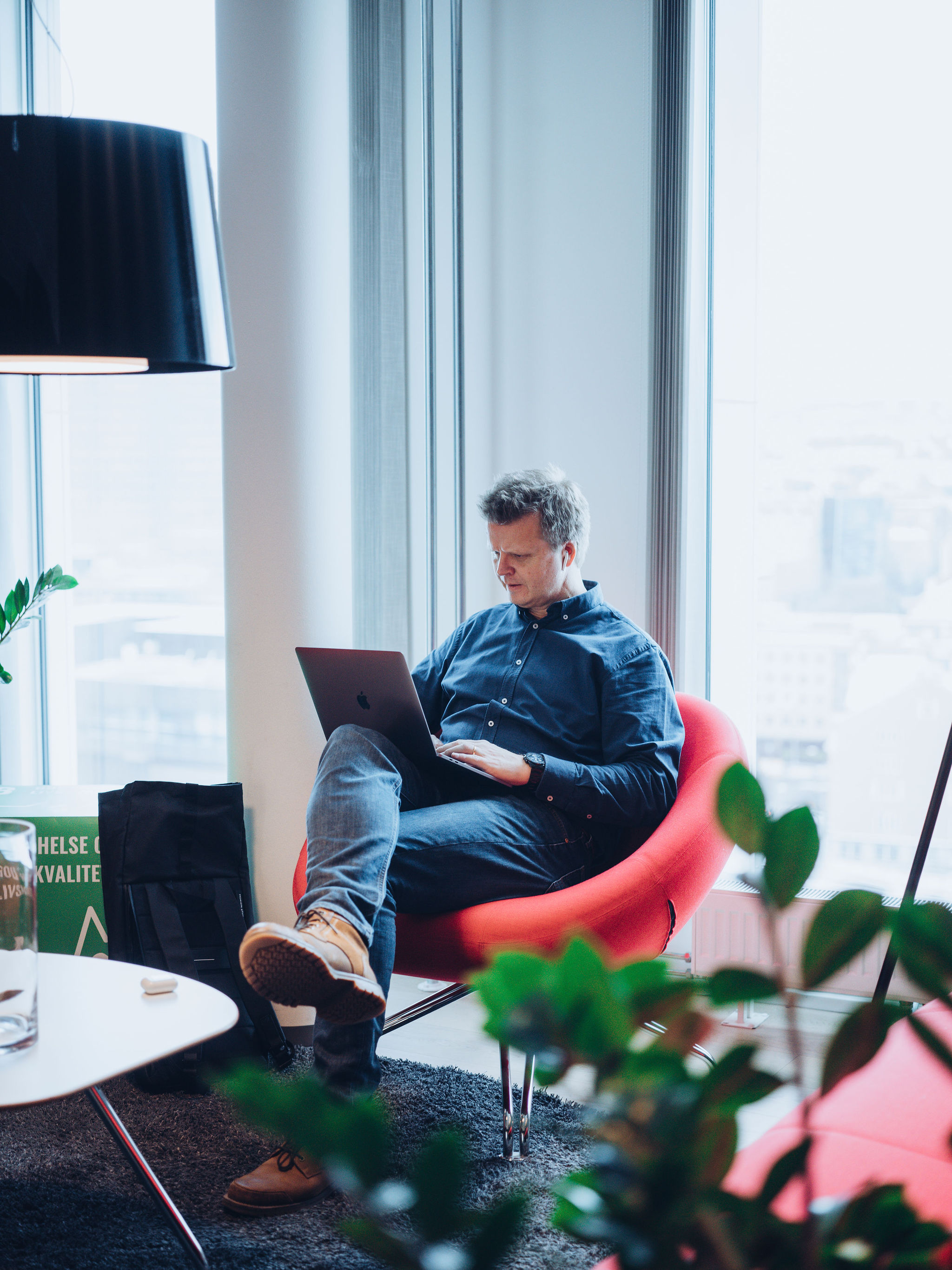 Mann i rød stol med laptop på fanget