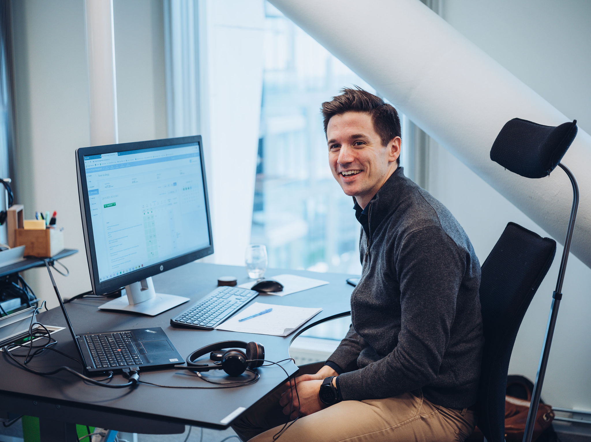 Smilende mann foran PC-skjerm