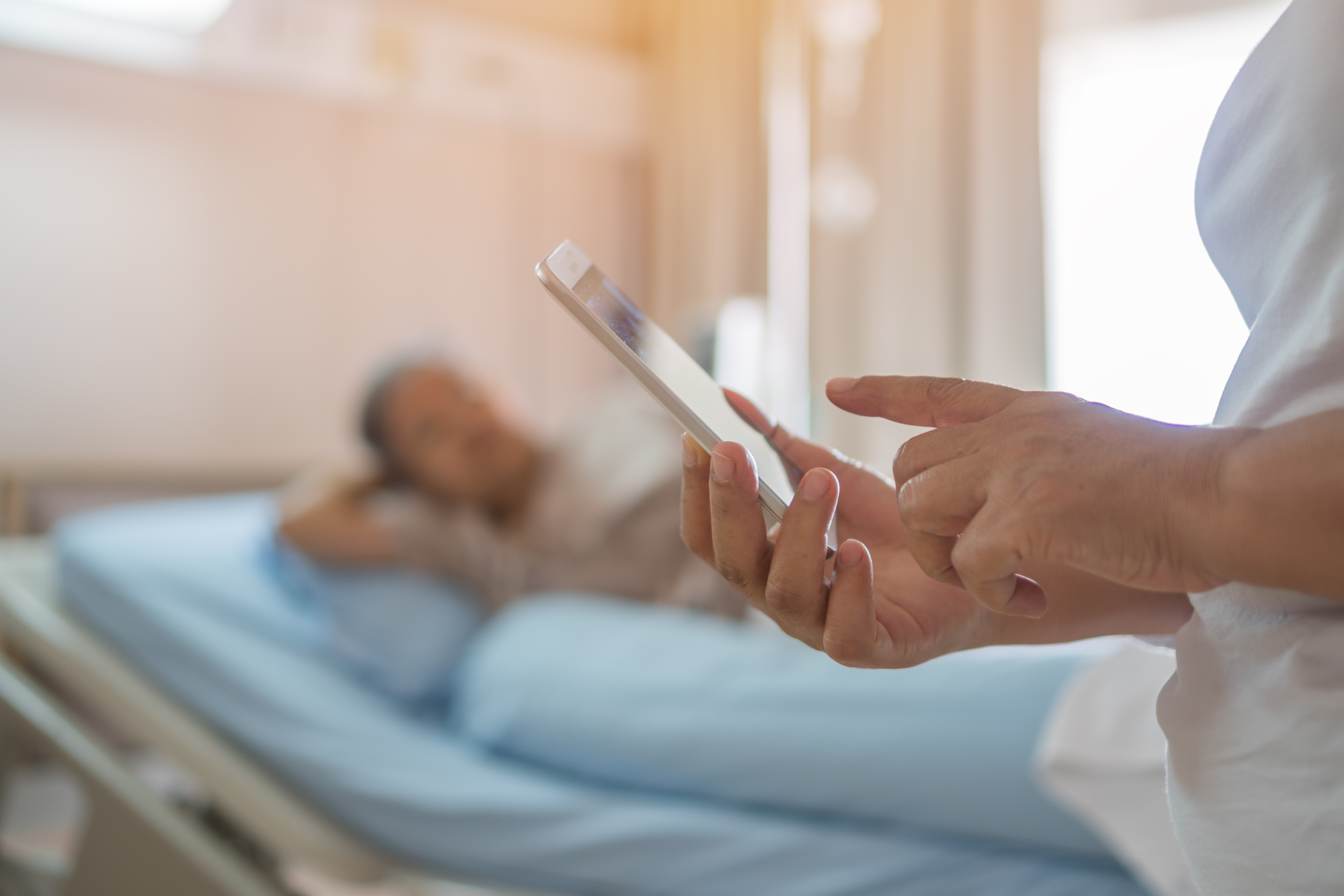 Sykepleier med telefon i front av pasient