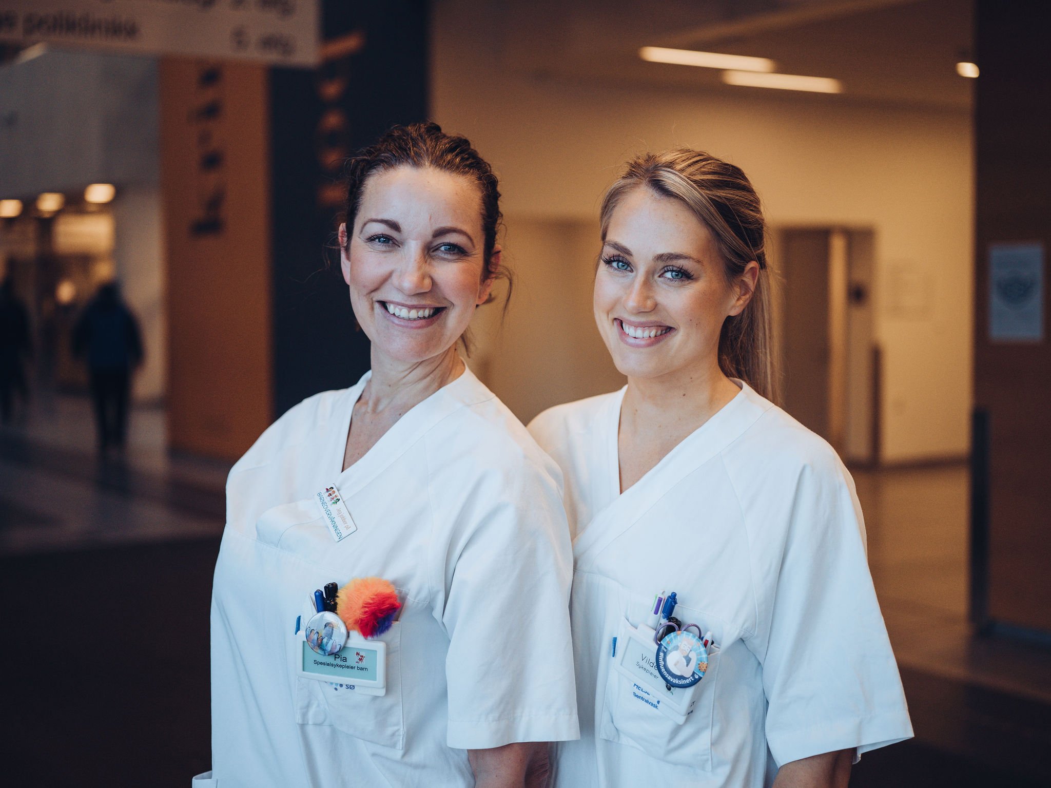 To smilende sykepleiere i alleen på Ahus 1